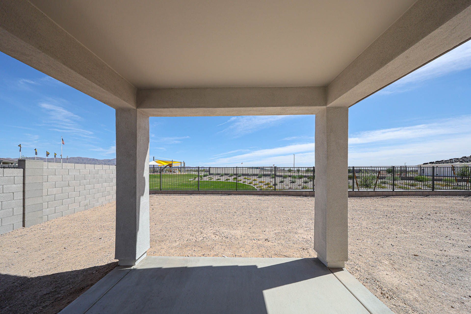 A concrete archway with a fence and a beach and a boat in the distance.