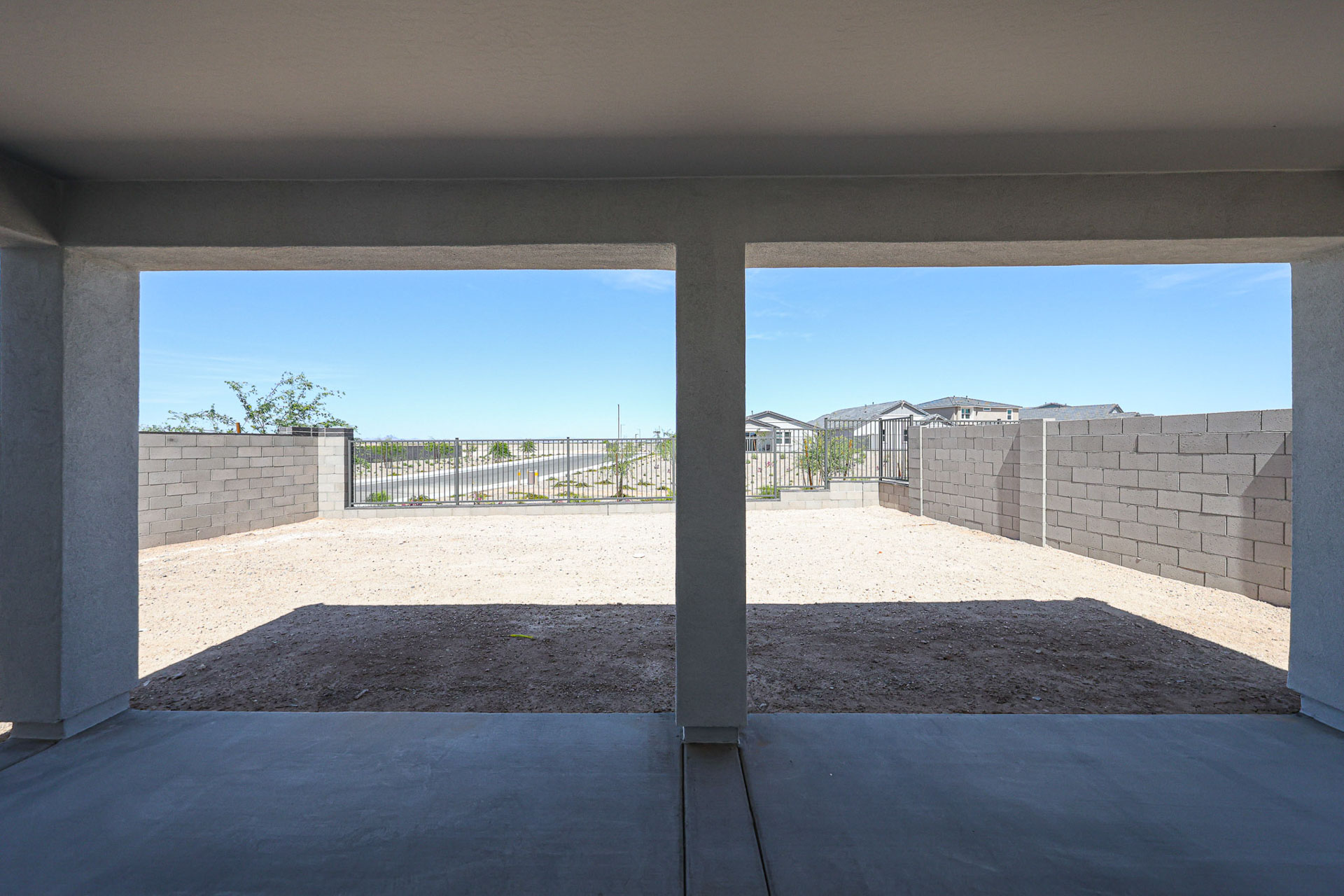 A view of a patio with a fence and a stone wall with Barcelona Pavilion in the background.