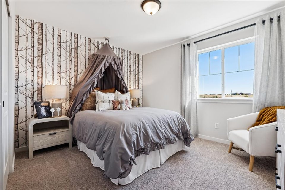 A bedroom with a bed and a chair.