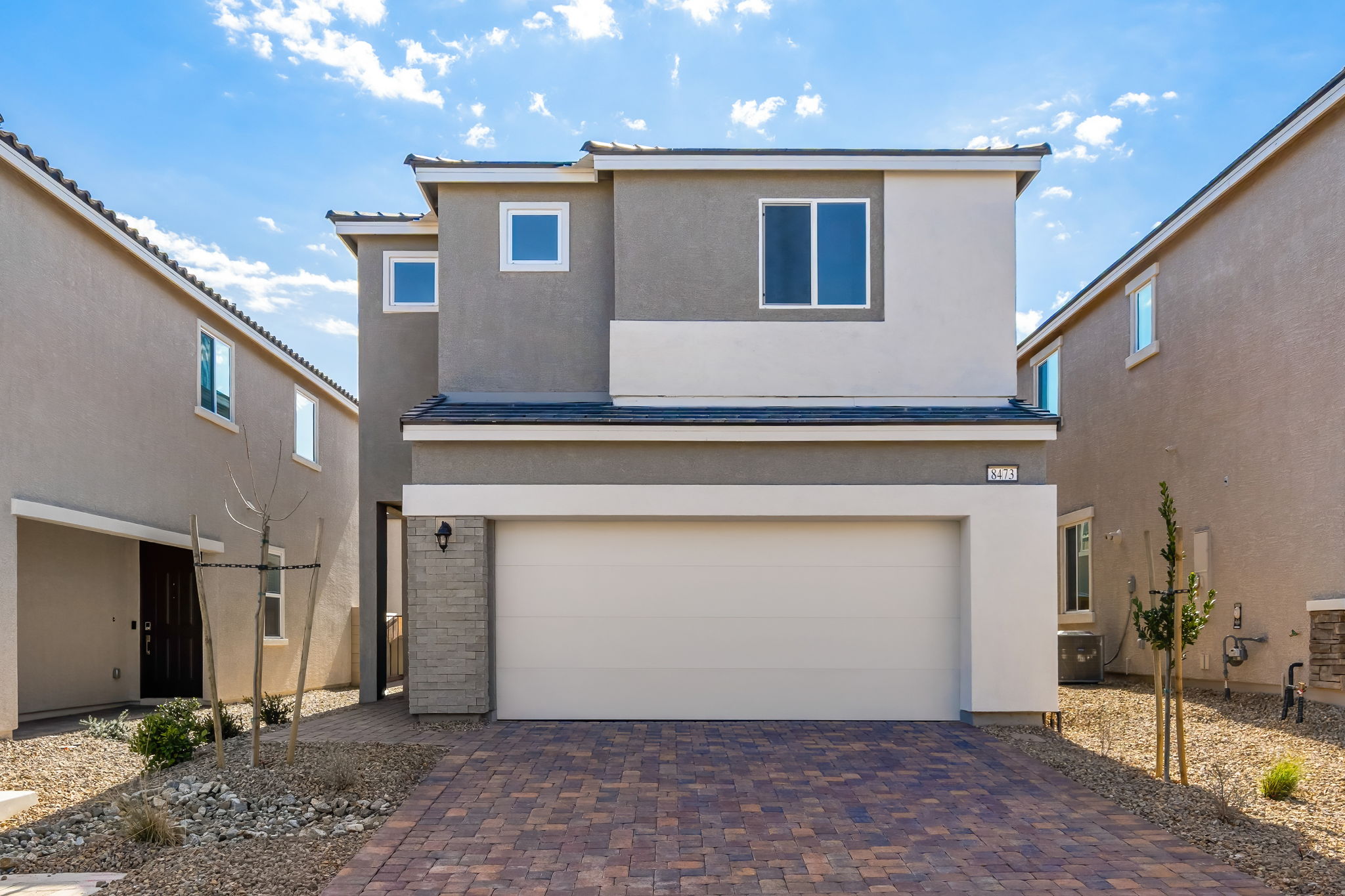 A white garage with a brick driveway.