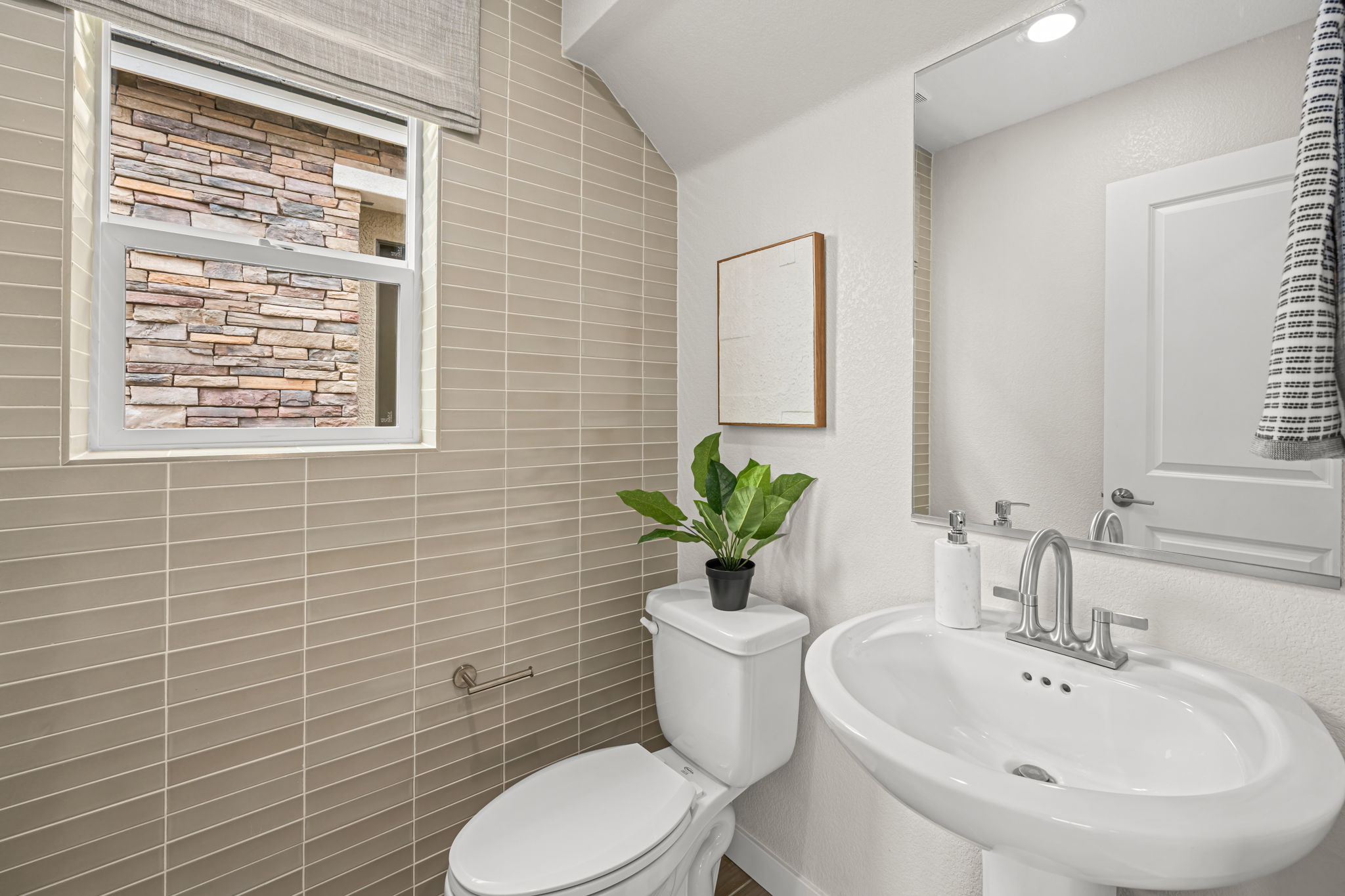 A bathroom with a plant on the toilet.