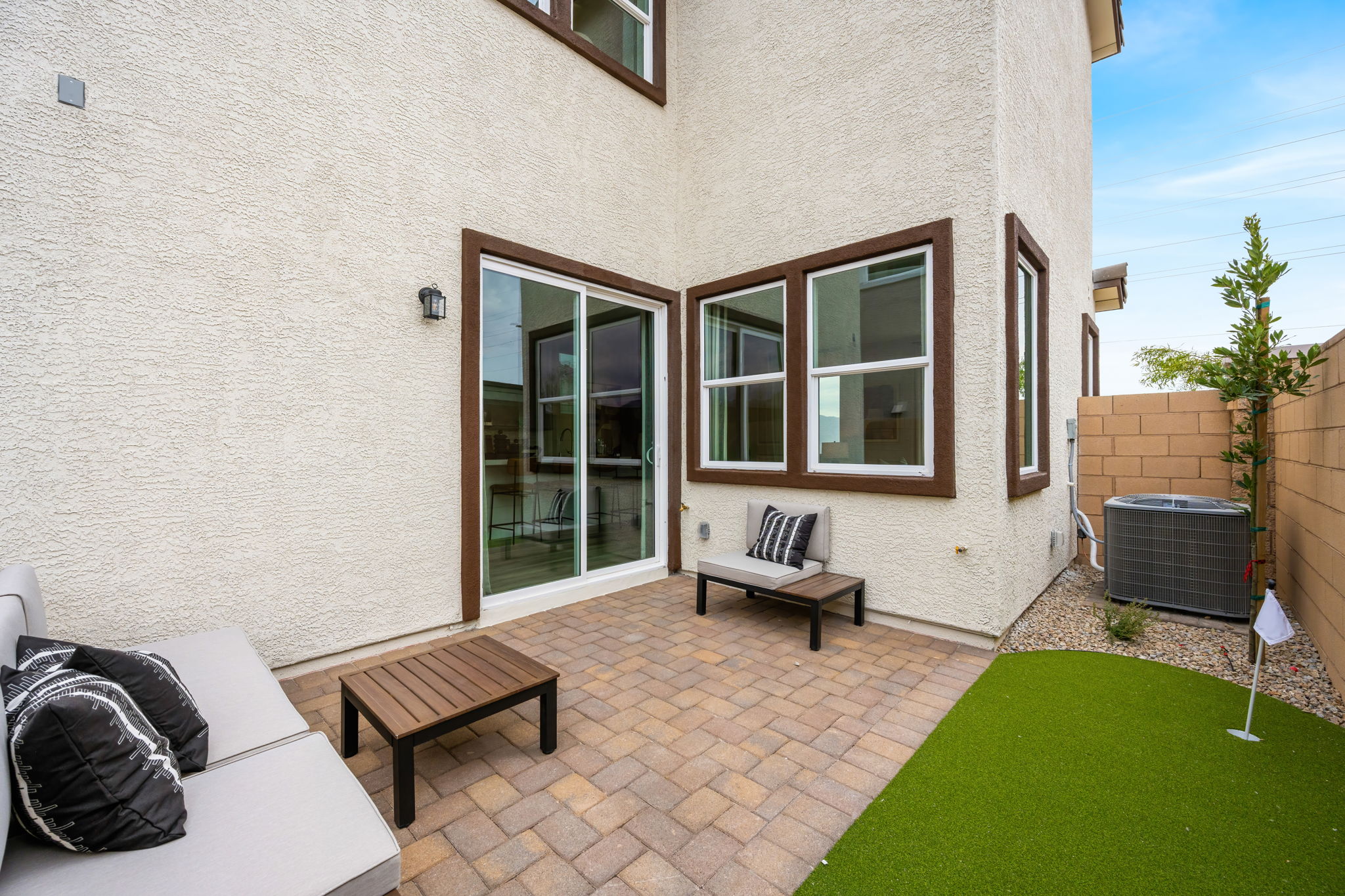 A patio with a bench and a table and a large window.