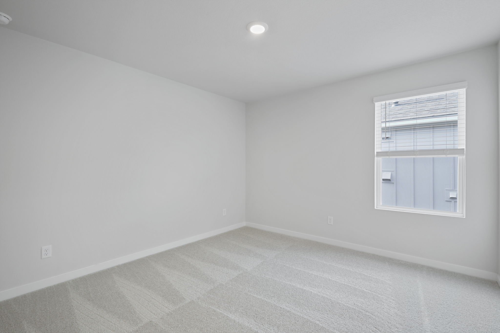 A room with a window and a white wall.