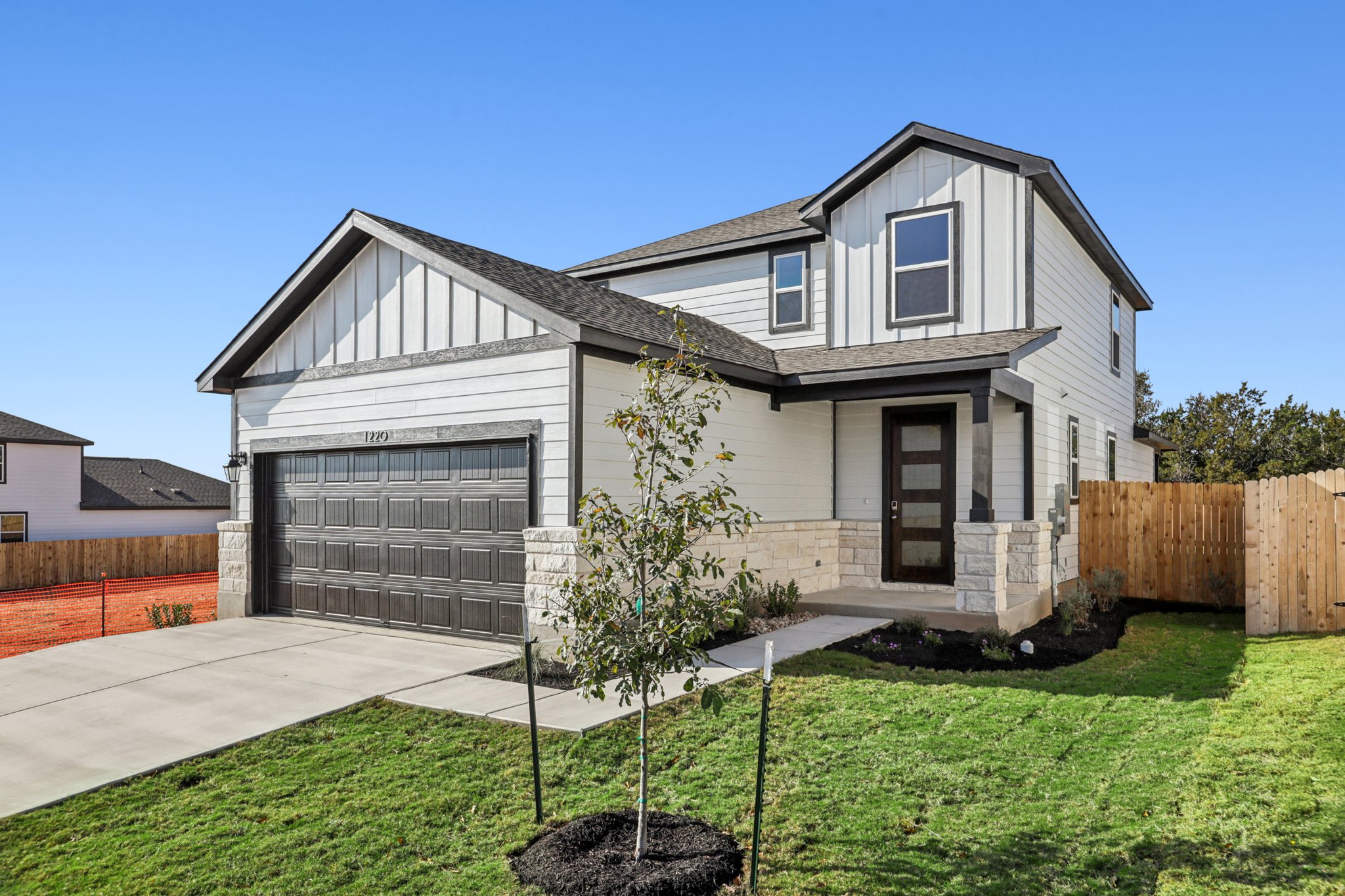 A house with a fence and a tree in the front.