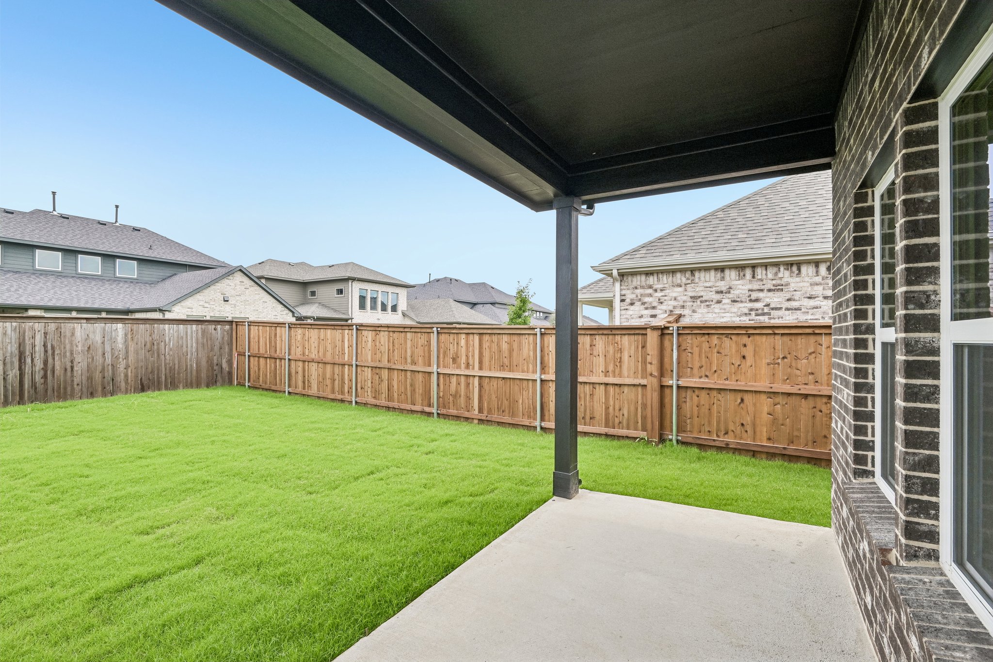 A backyard with a fence and a house.
