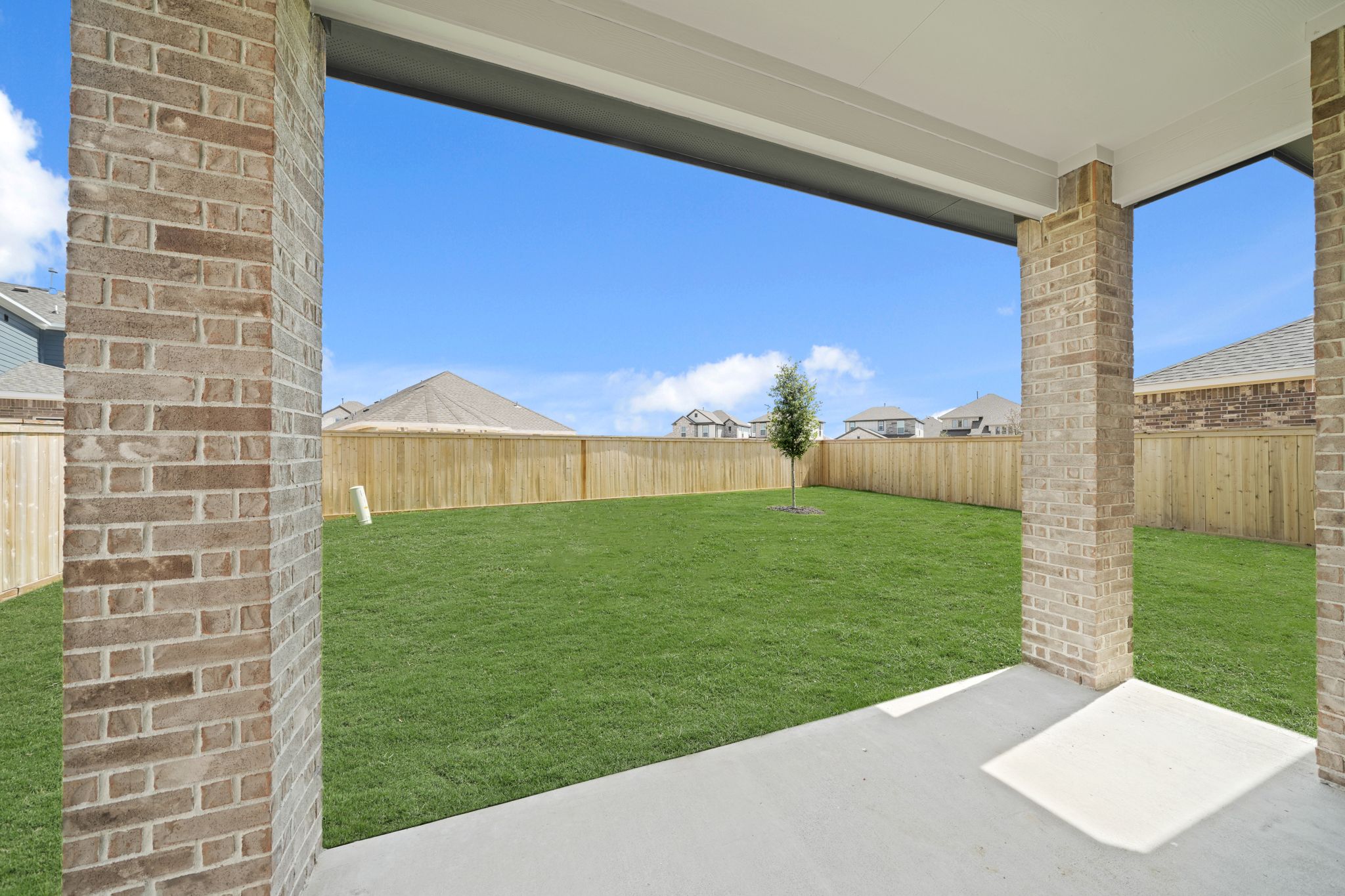 A backyard with a fence and a grass yard.
