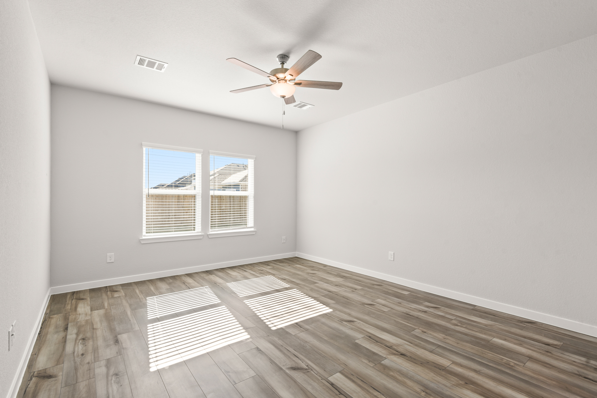 A room with a ceiling fan and a wood floor.