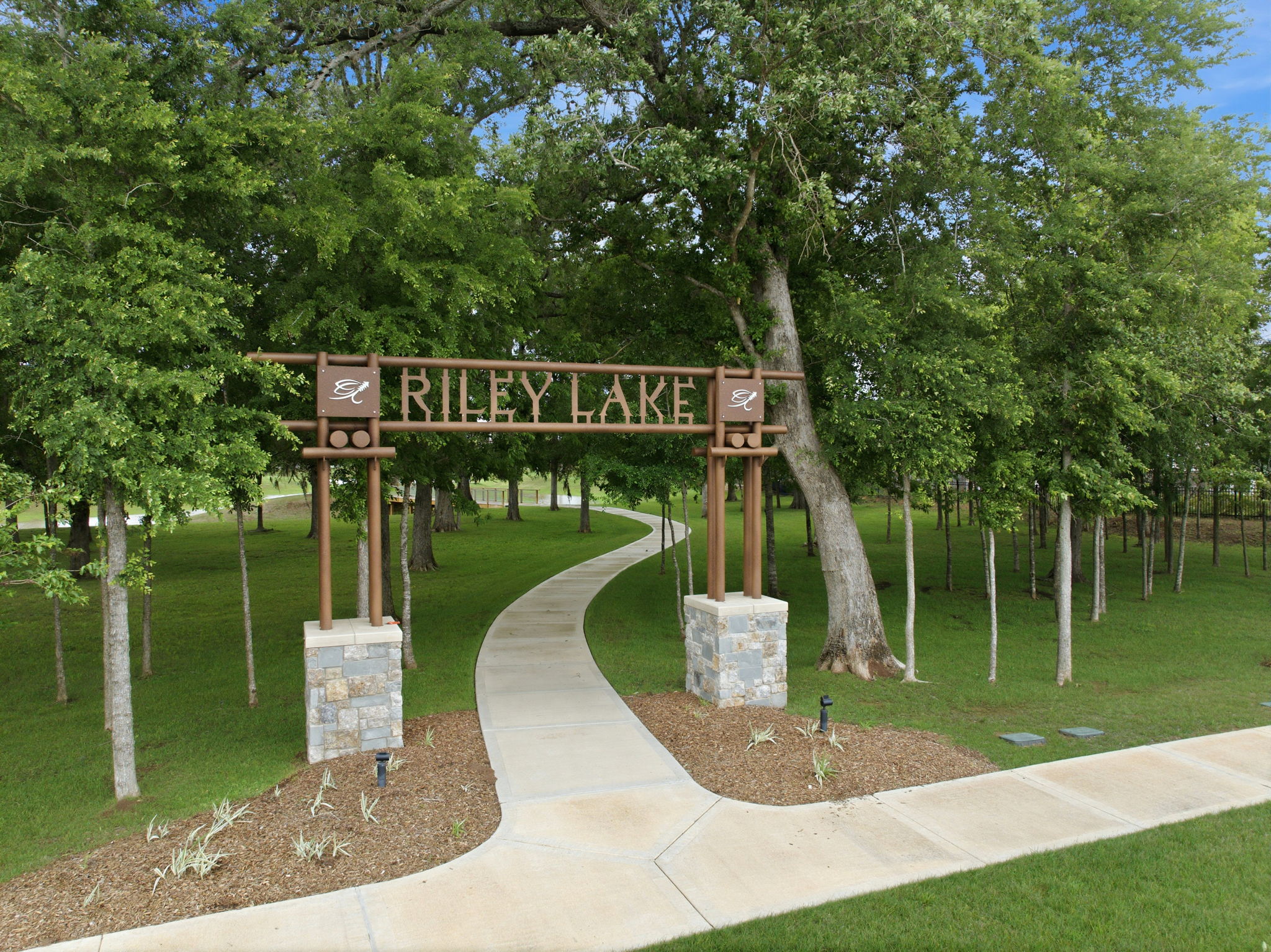 A wooden walkway with a sign on it surrounded by trees.