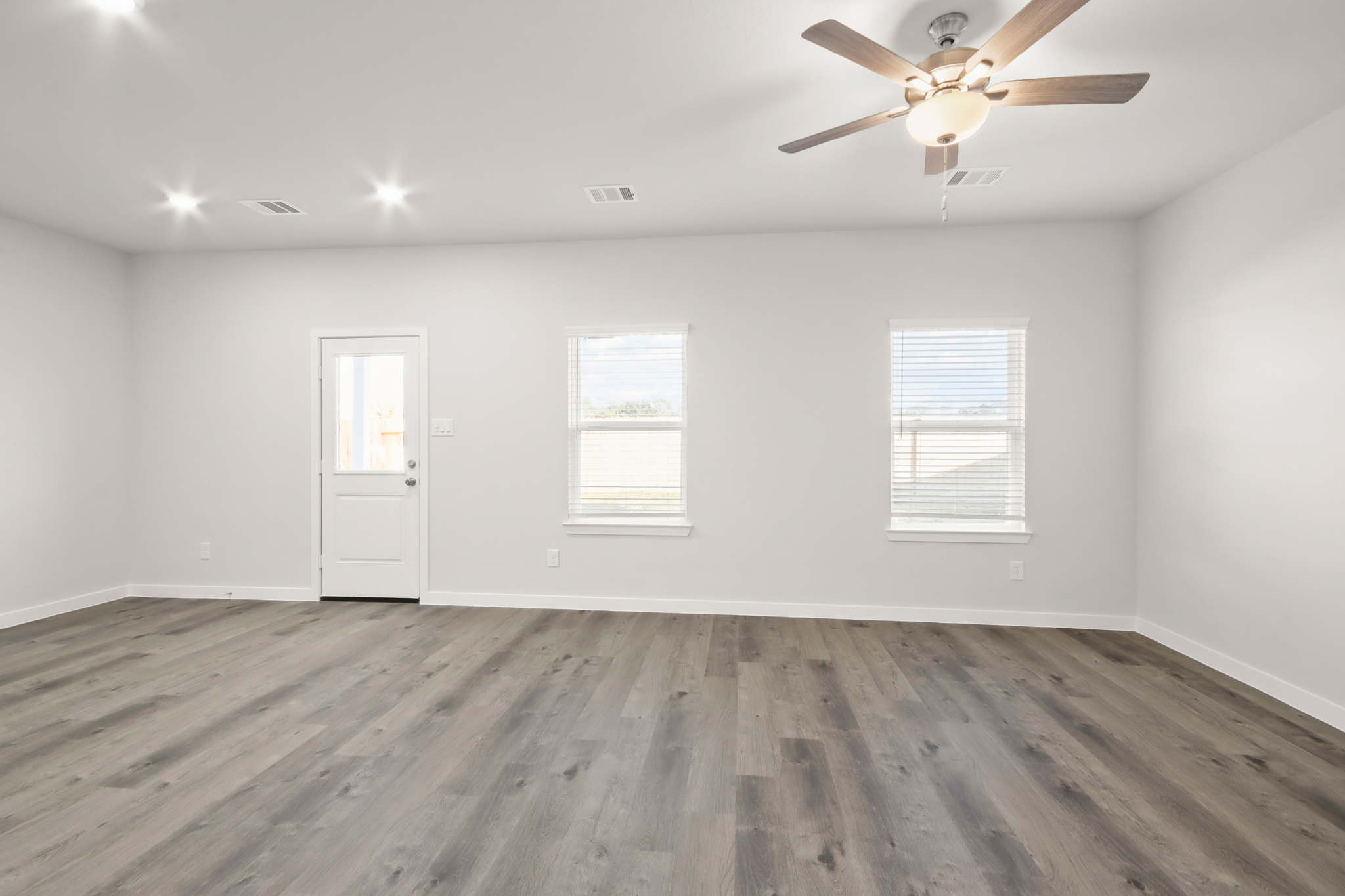 A room with a ceiling fan and a wood floor.