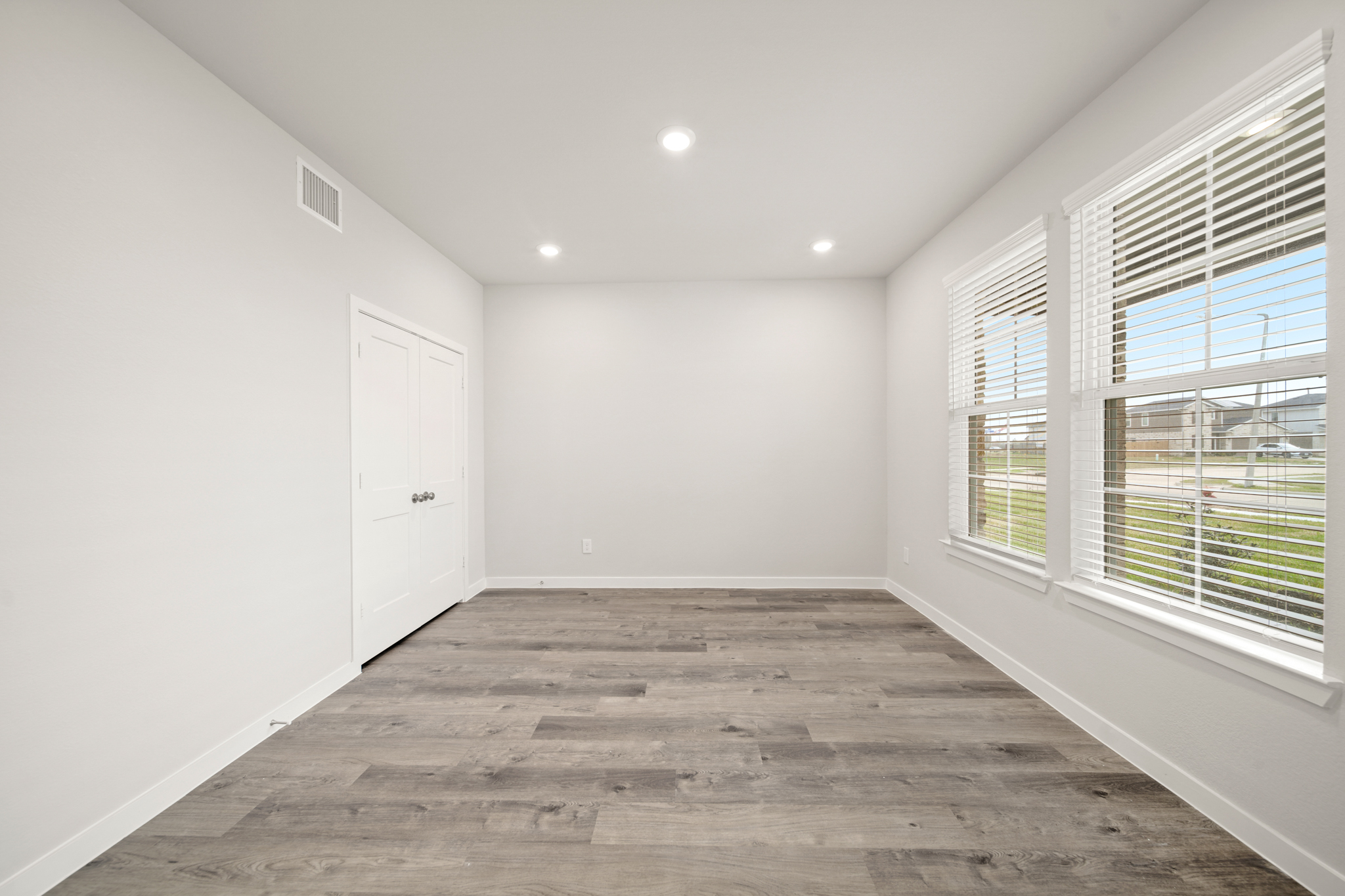 A room with windows and a wood floor.