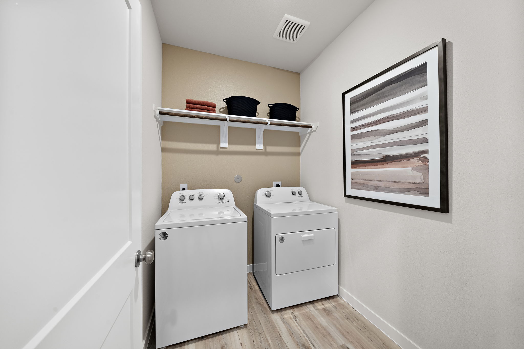 A room with a shelf and a white cabinet with a white door.