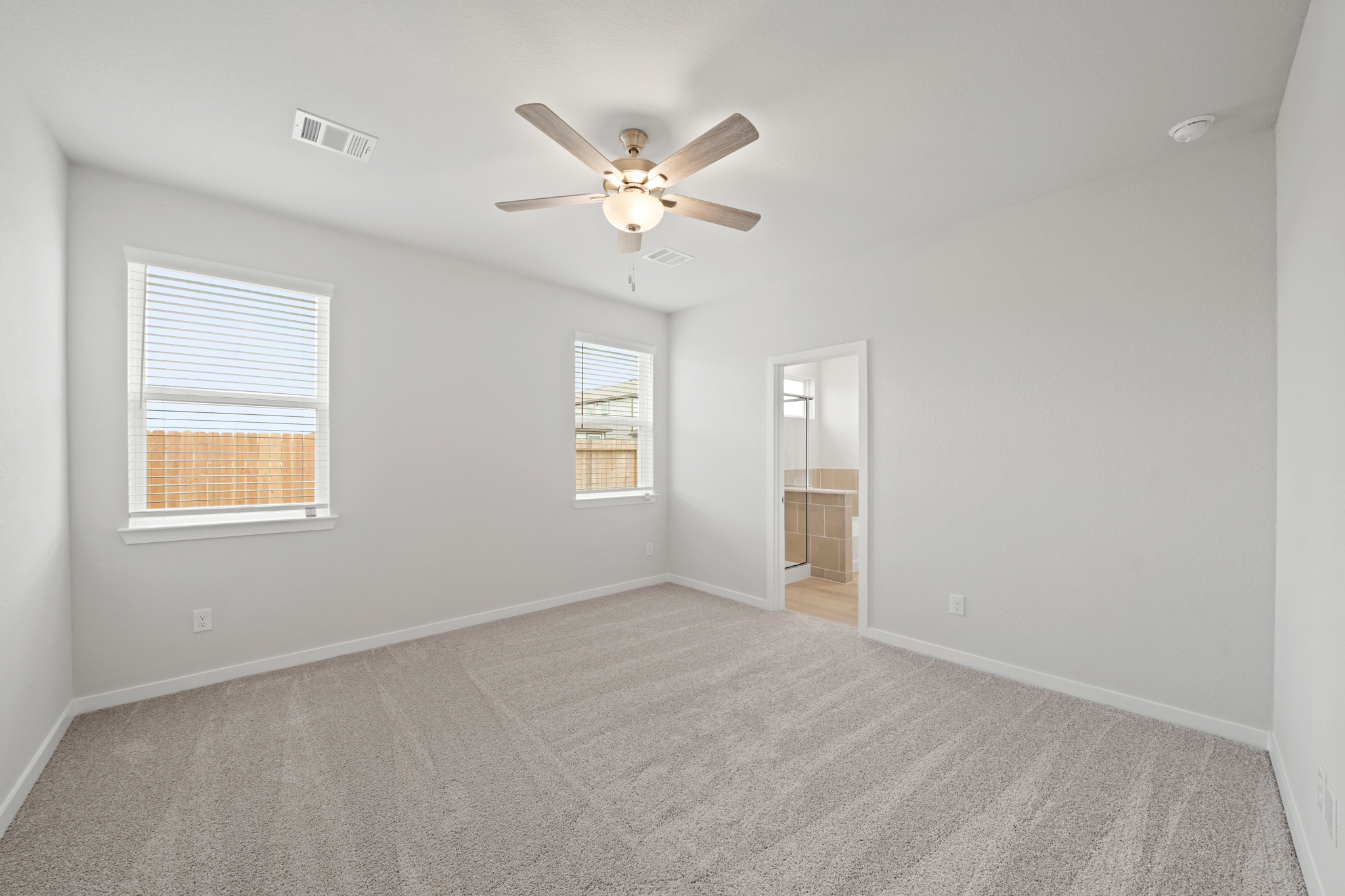 A room with a ceiling fan and a carpet.