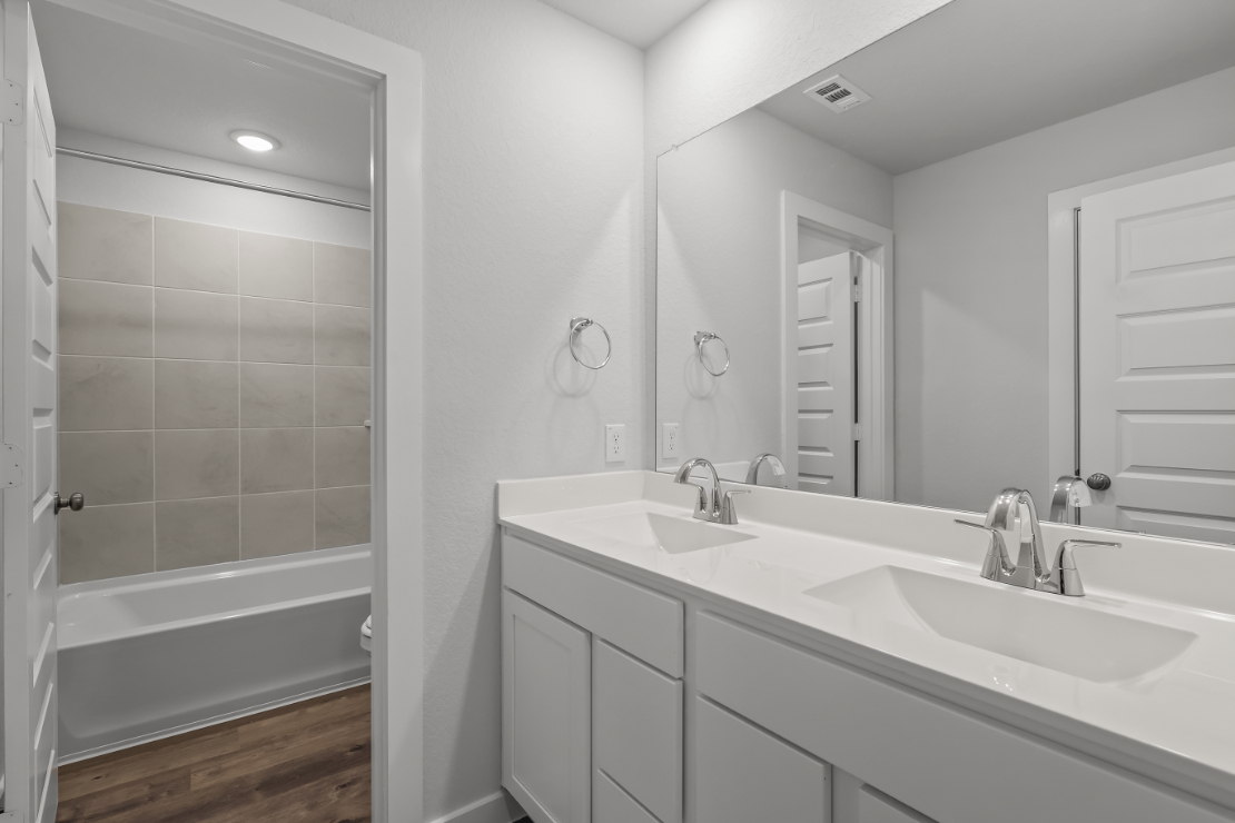 A bathroom with a tub sink and a mirror.
