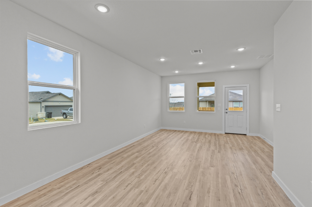 A room with a wood floor and a window with a view of the water.