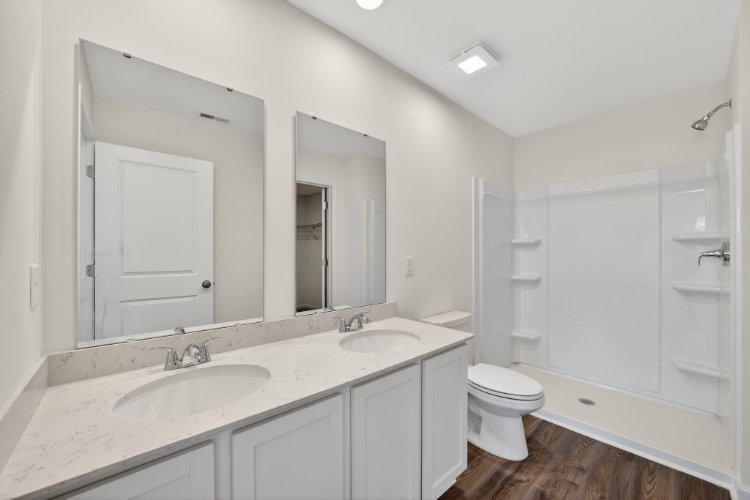 A bathroom with a sink toilet and mirror.