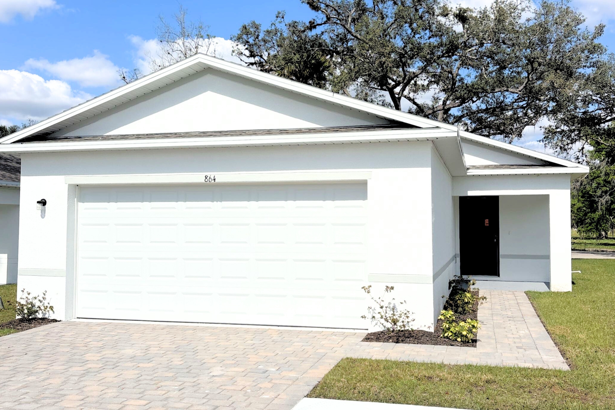A white garage with a brick walkway.